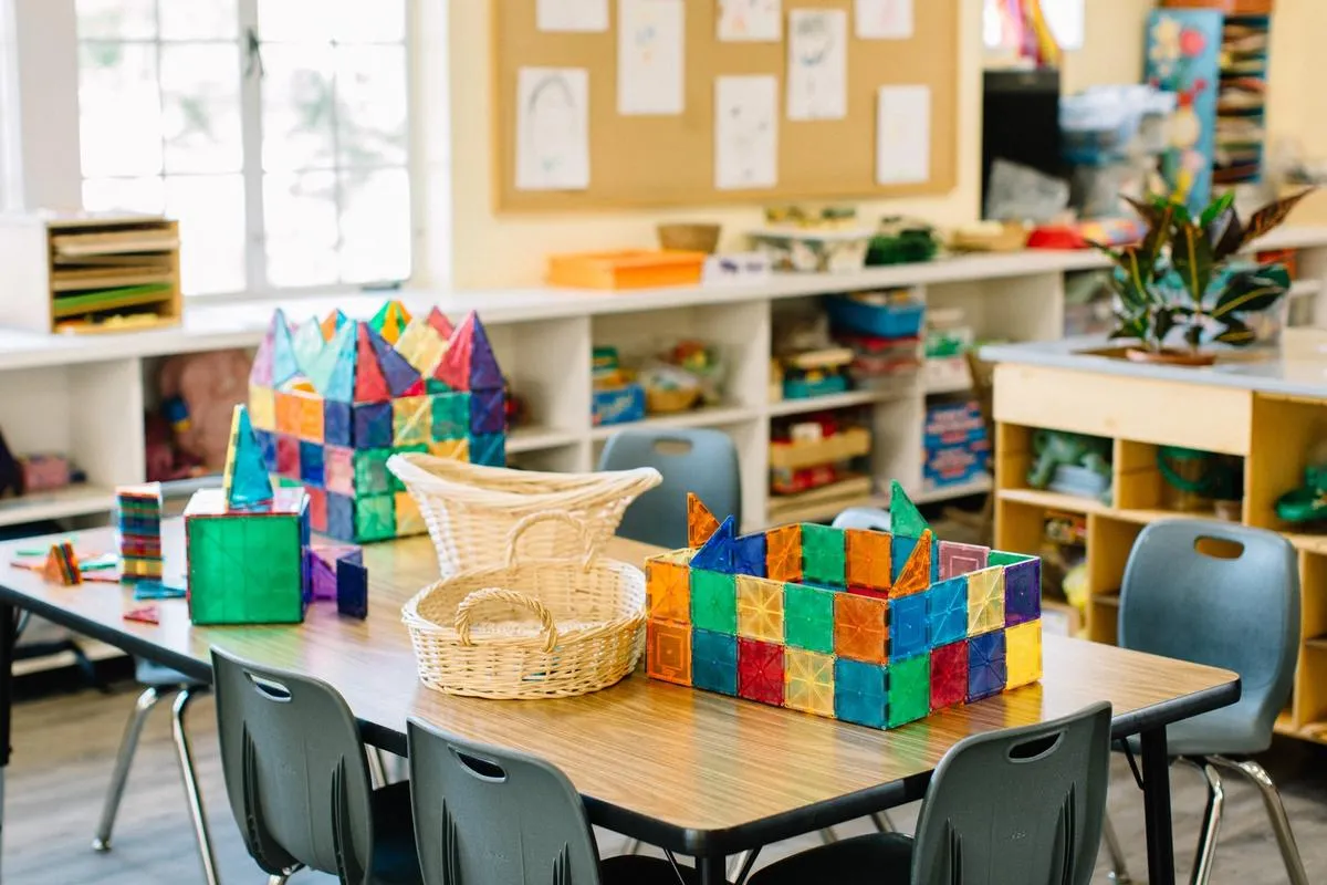 An empty classroom with geometric shape games and baskets on a child-size work table.